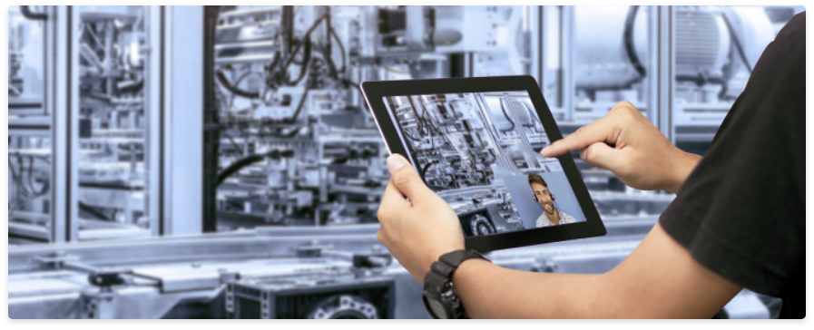 Technicien utilisant une tablette pour échanger en visio avec un expert devant une machine industrielle